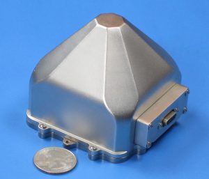 Small metallic inertial navigation systems placed next to a quarter for size comparison